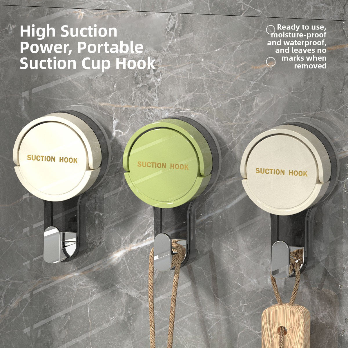 Cream, green and white suction cup hooks on a gray marble wall holding a cord and a wooden brush