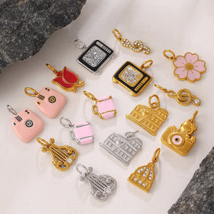 Gold and silver enamel and rhinestone charm pendants arranged on dark stone and cream backdrop