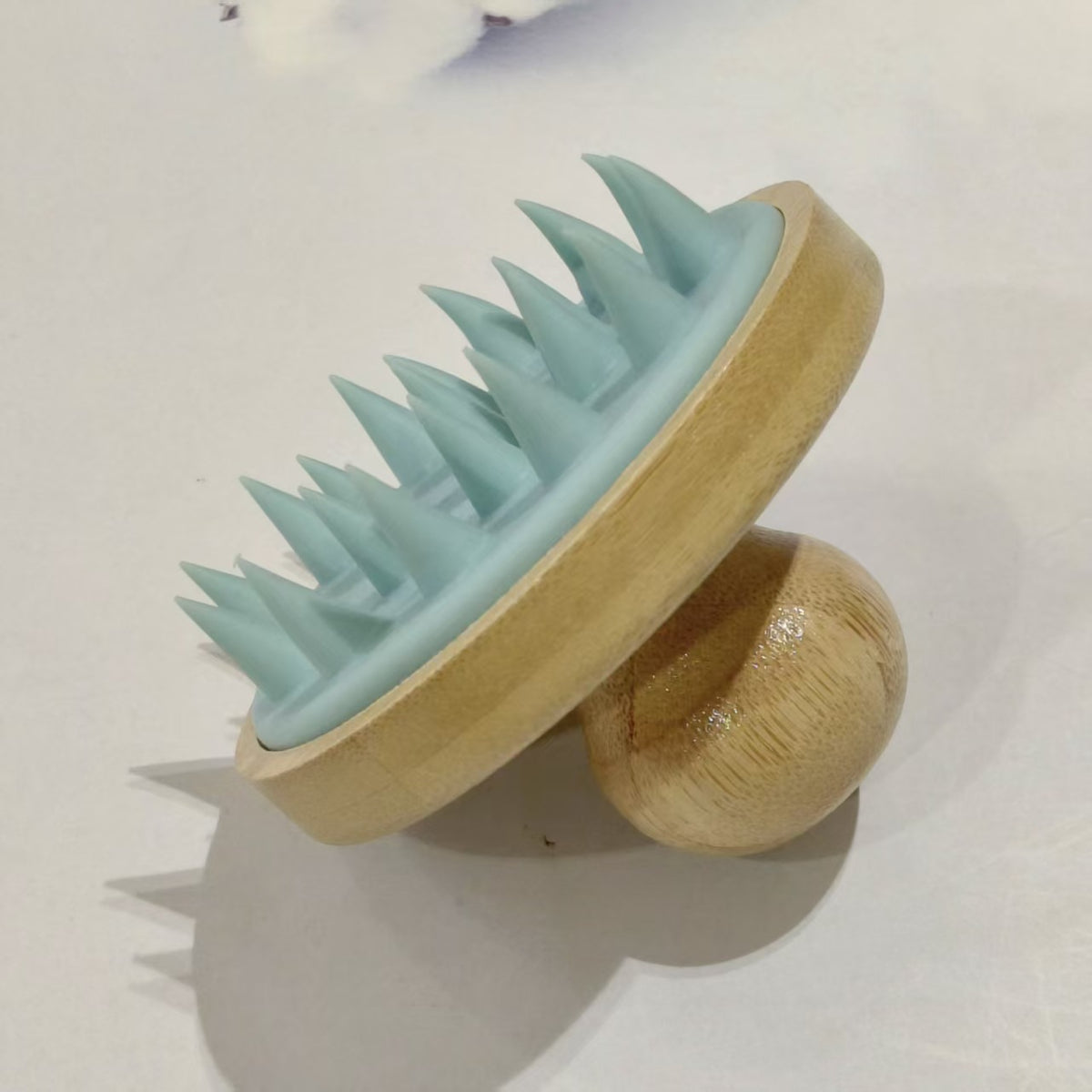 Blue bamboo and silicone scalp massage brush with a domed wooden knob grip