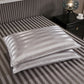 Navy blue stripe satin pillowcase resting against a headboard