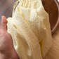 Pale yellow cotton linen pants held to show the soft open weave texture