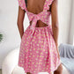 Floral square neck mini dress showing the open back that ties with a bow, standing outdoors