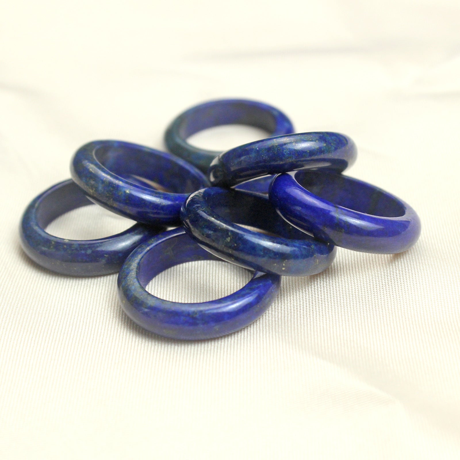 Deep blue polished lapis lazuli band ring showing natural gold flecks across the solid stone surface