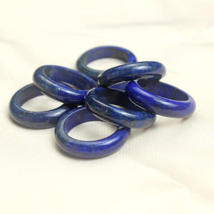 Deep blue polished lapis lazuli band ring showing natural gold flecks across the solid stone surface