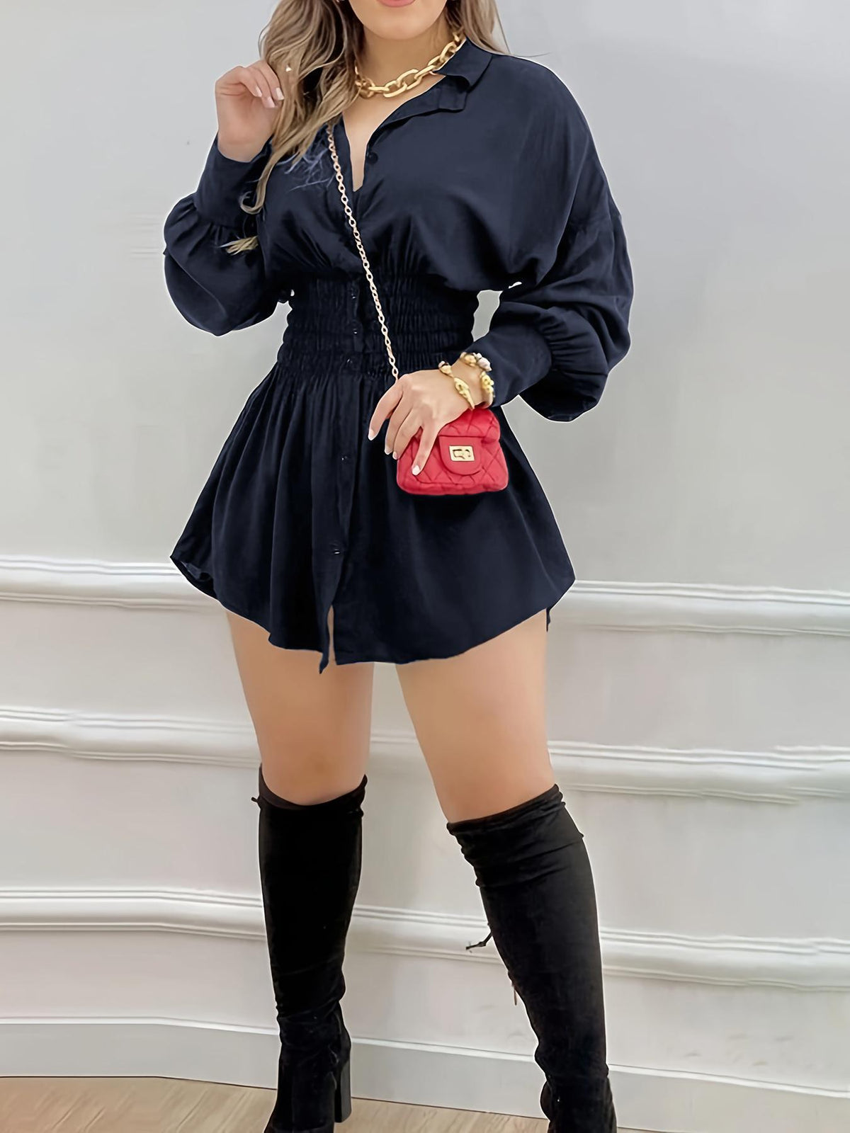 Navy blue button front mini shirt dress with smocked waist and long sleeves, with tall black boots and a red bag