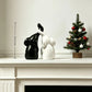 Couple elephant figurines shown about 12 cm tall on a mantel beside a small decorated tree