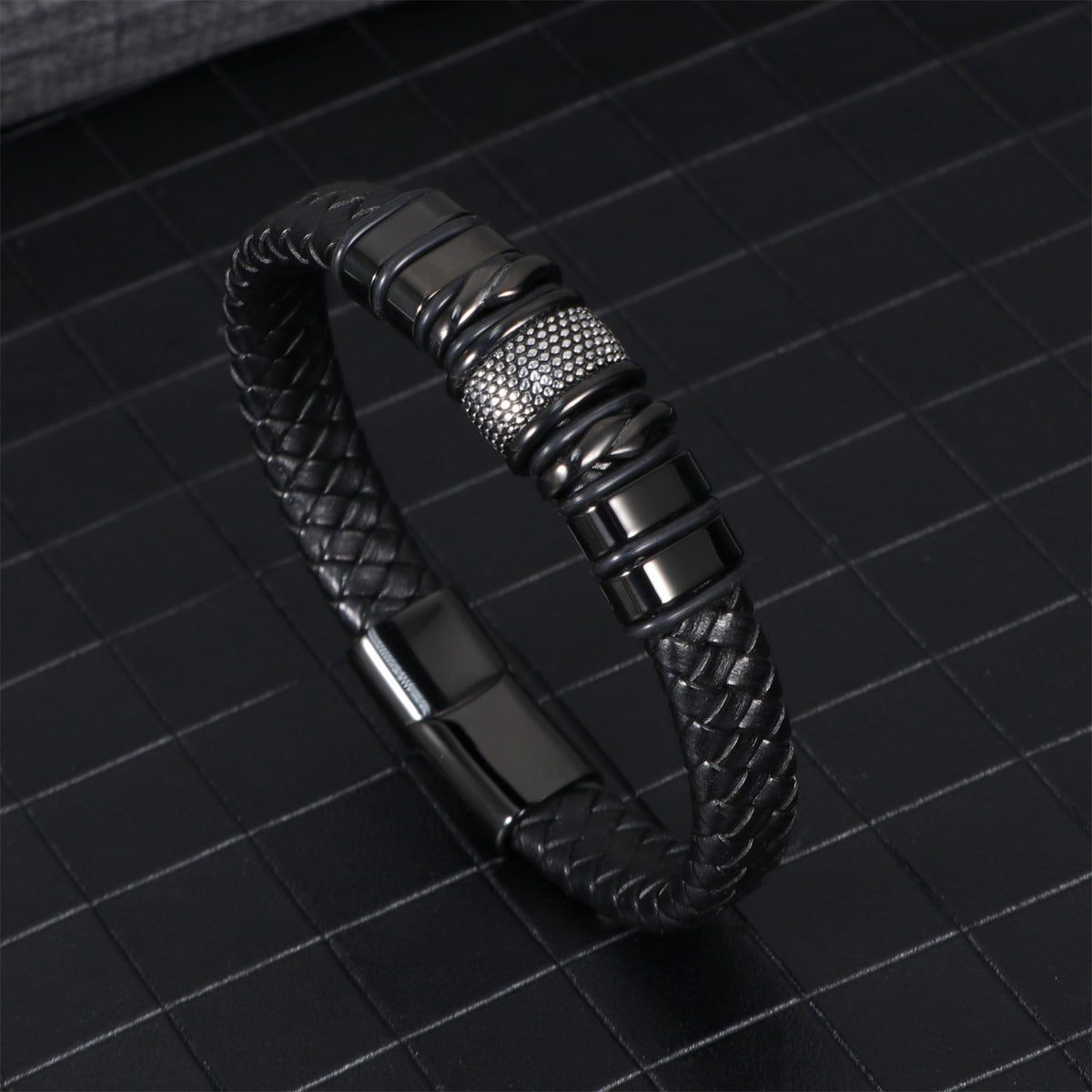 Black braided leather bracelet coiled to show the woven strands and steel clasp