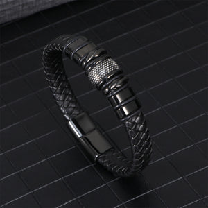 Black braided leather bracelet coiled to show the woven strands and steel clasp