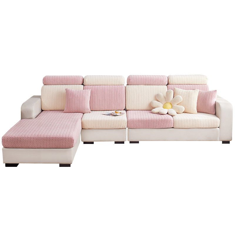 Pink and ecru herringbone jacquard stretch covers fitted over a sectional sofa front view