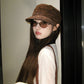 Cream vegan suede flat top cap held in hand, close view of the nap