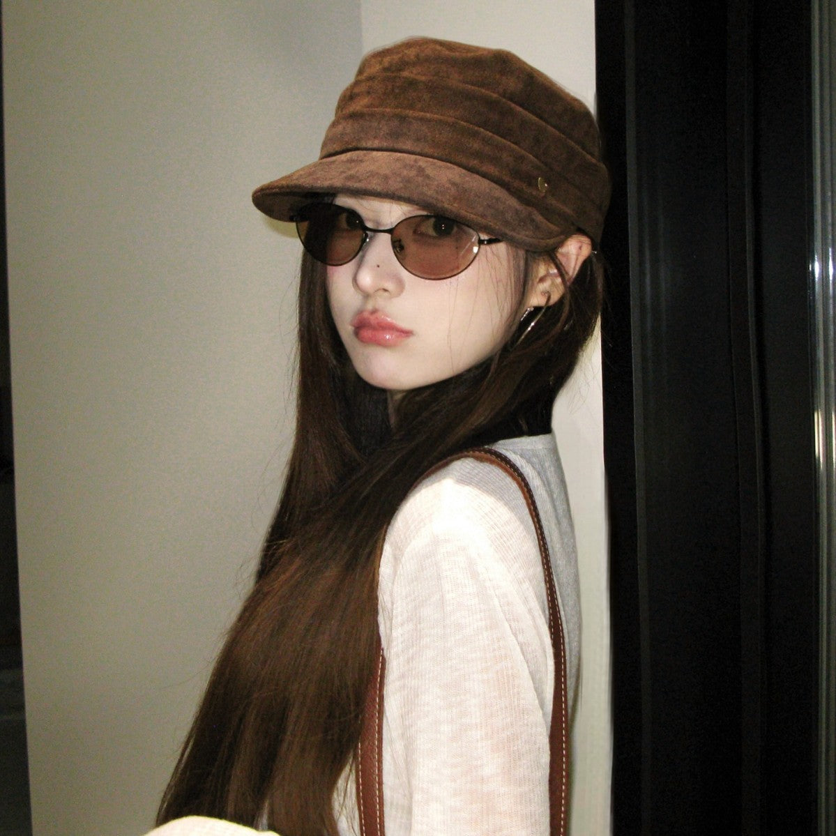 Cream vegan suede flat top cap held in hand, close view of the nap