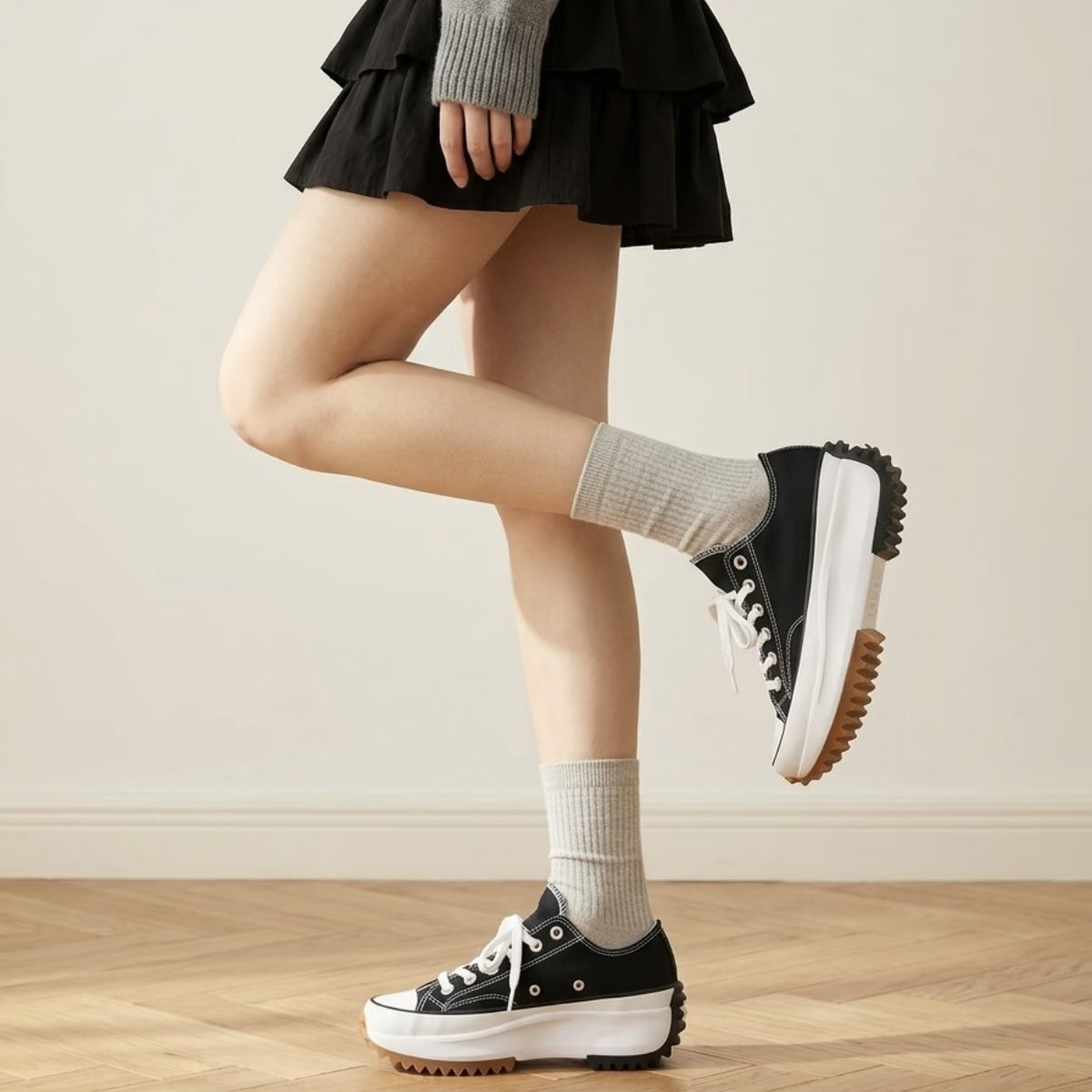 Black low-top platform canvas sneakers in two poses with a chunky white sole, worn with a black ruffle skirt
