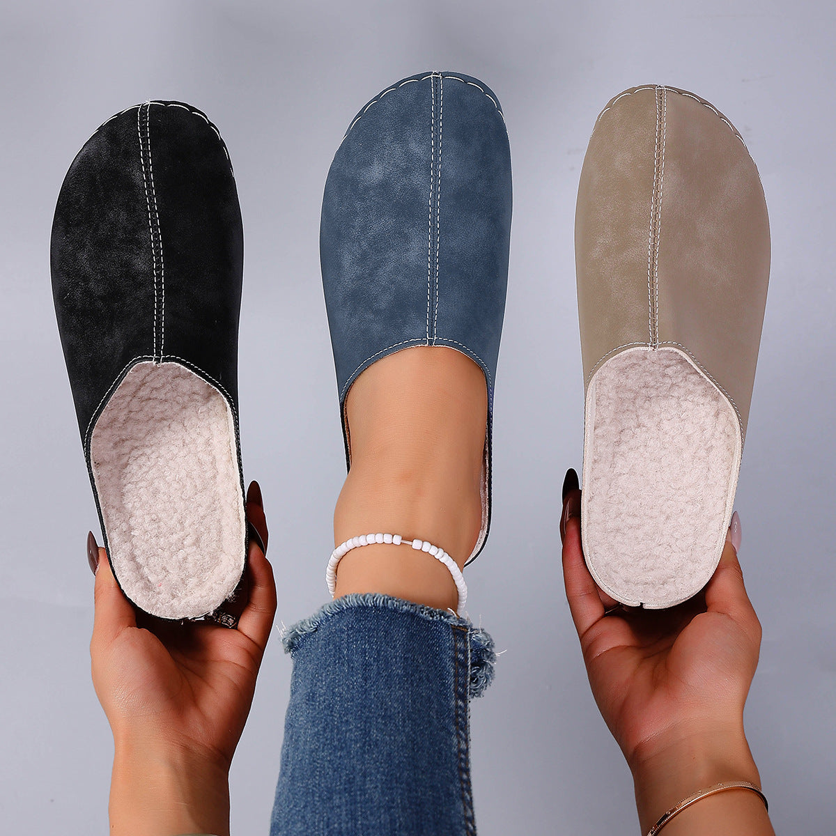 Womens fleece lined slip on mule clogs shown in blue, black and khaki, held in hand