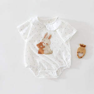 White cotton short sleeve baby romper with gray polka dots and a rabbit hugging a bear print, flat lay