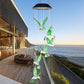 Green hummingbird LED figures hanging from a solar lamp head on a deck at dusk, black housing option