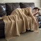 Khaki cotton gauze throw blanket with tassel fringe, draped over a woman asleep on a dark sofa, view 4 of 4