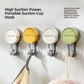 Four suction cup hooks in cream, yellow, white and green on a wall holding a towel and a bath sponge