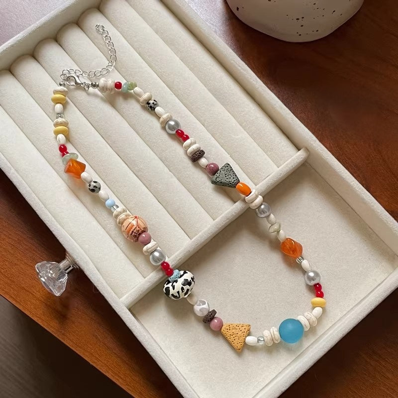 Multicolor beaded necklace with pearls and charms laid out in a jewelry box