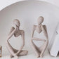 Abstract resin meditator figurine seated in a contemplative thinking pose as minimal shelf decor