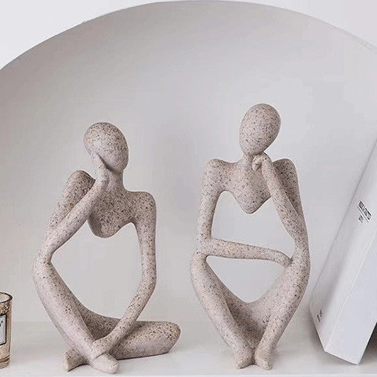 Abstract resin meditator figurine seated in a contemplative thinking pose as minimal shelf decor