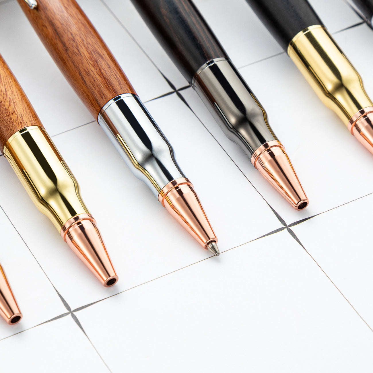 Close up of the copper toned bullet shaped noses on several wood barrel bolt action pens