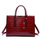 Red wine glossy croc pattern handbag with two top handles, buckled tab and shoulder strap, front view