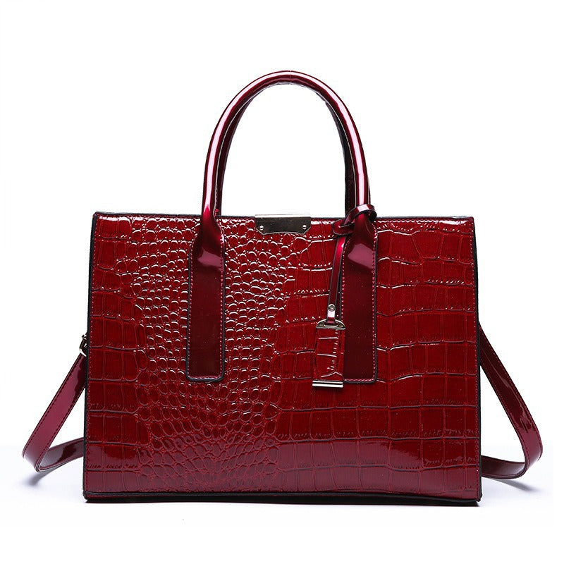 Red wine glossy croc pattern handbag with two top handles, buckled tab and shoulder strap, front view