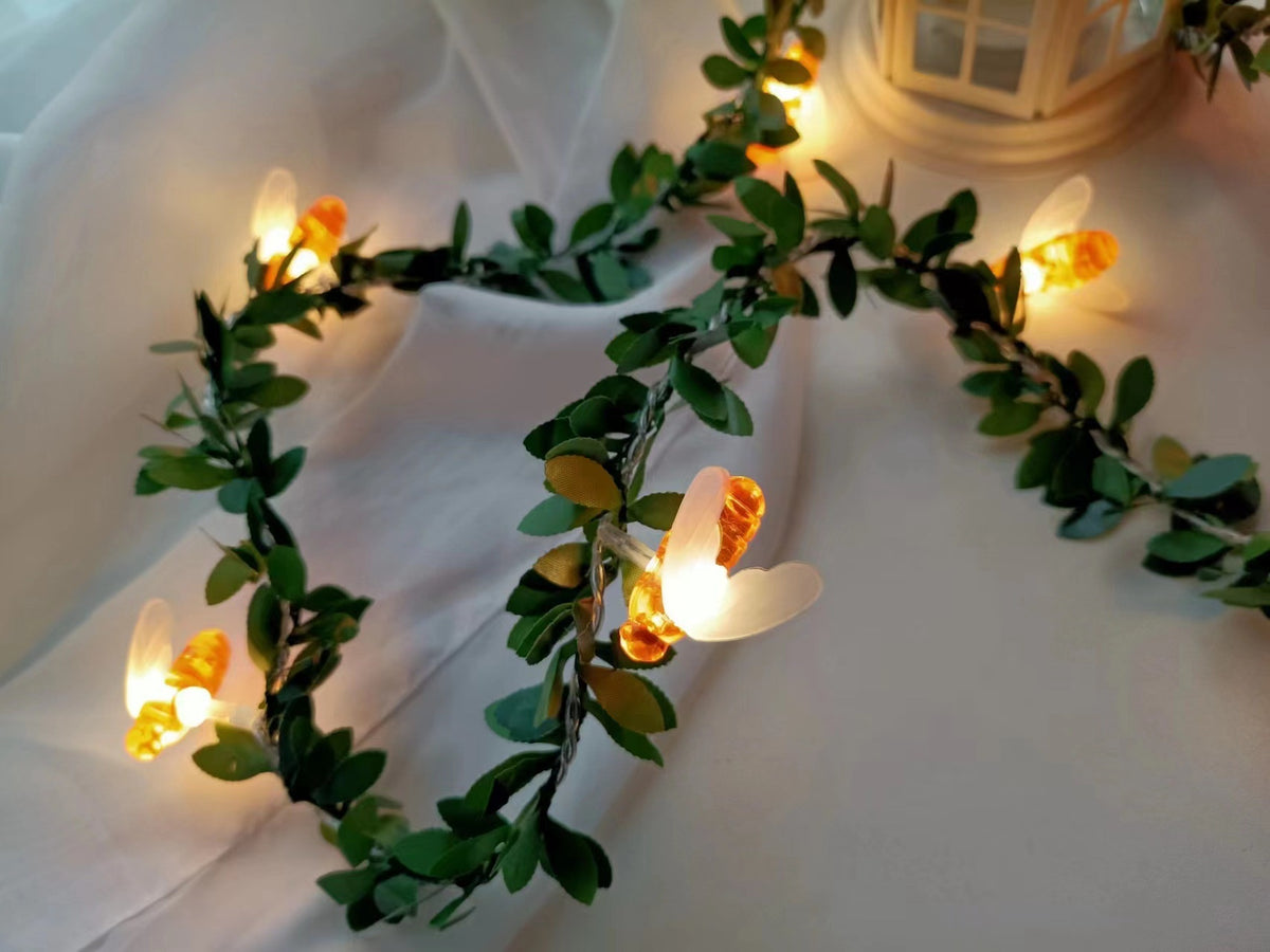 Bee LED fairy string light on a green leaf vine with a warm glow, decorative photo