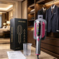 Gray and fuchsia handheld garment steamer in a holder beside its box, water cup and manual in a wardrobe