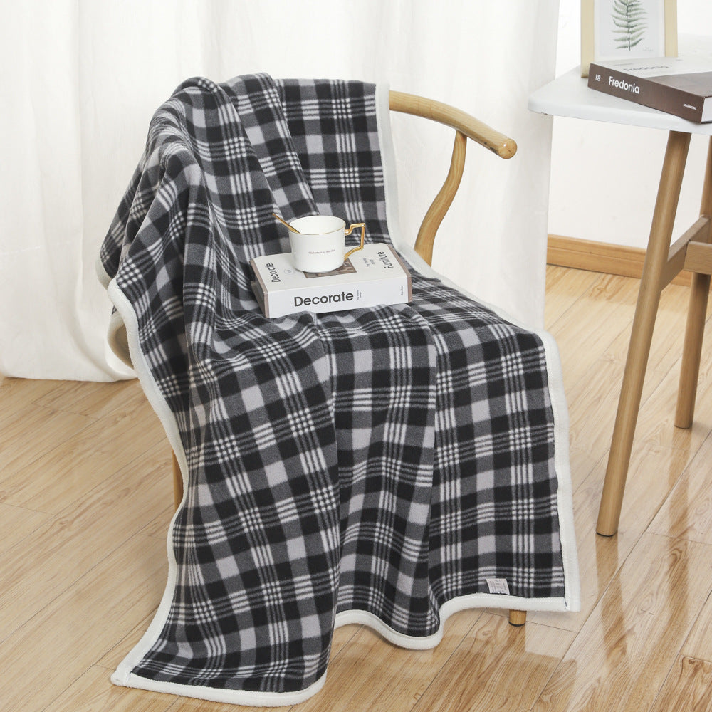 Gray and white plaid coral fleece blanket in 100 x 140 cm draped over a wooden chair