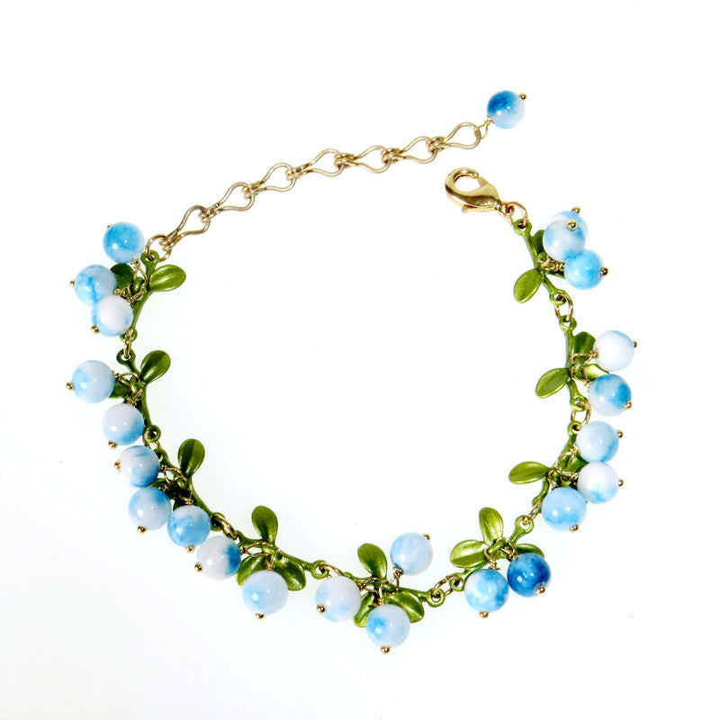Dark peach glossy berry beads bunched with green leaves on a chain bracelet