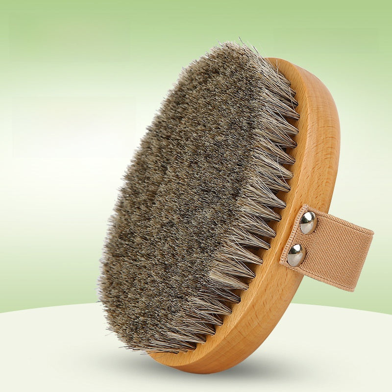 Oval horsehair body brush with a beech wood base and a beige hand strap on a green gradient background