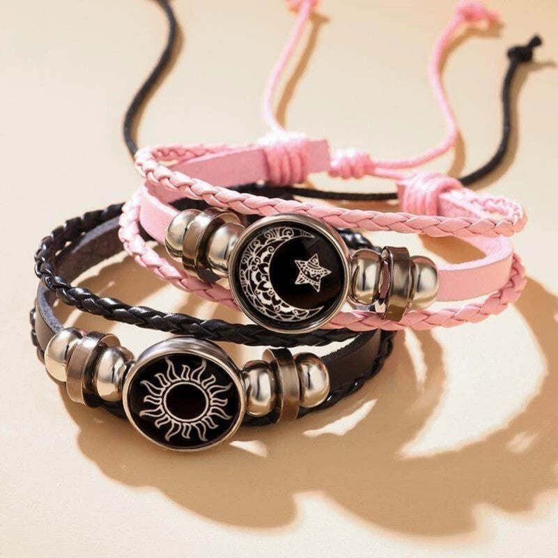 Pink and black braided cord bracelets with sun and moon charms stacked together