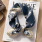 Navy blue geometric printed square scarf with a satin sheen and hemmed edges, shown displayed