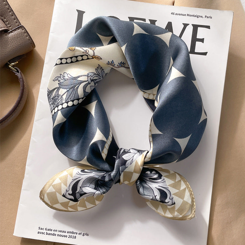 Navy blue geometric printed square scarf with a satin sheen and hemmed edges, shown displayed