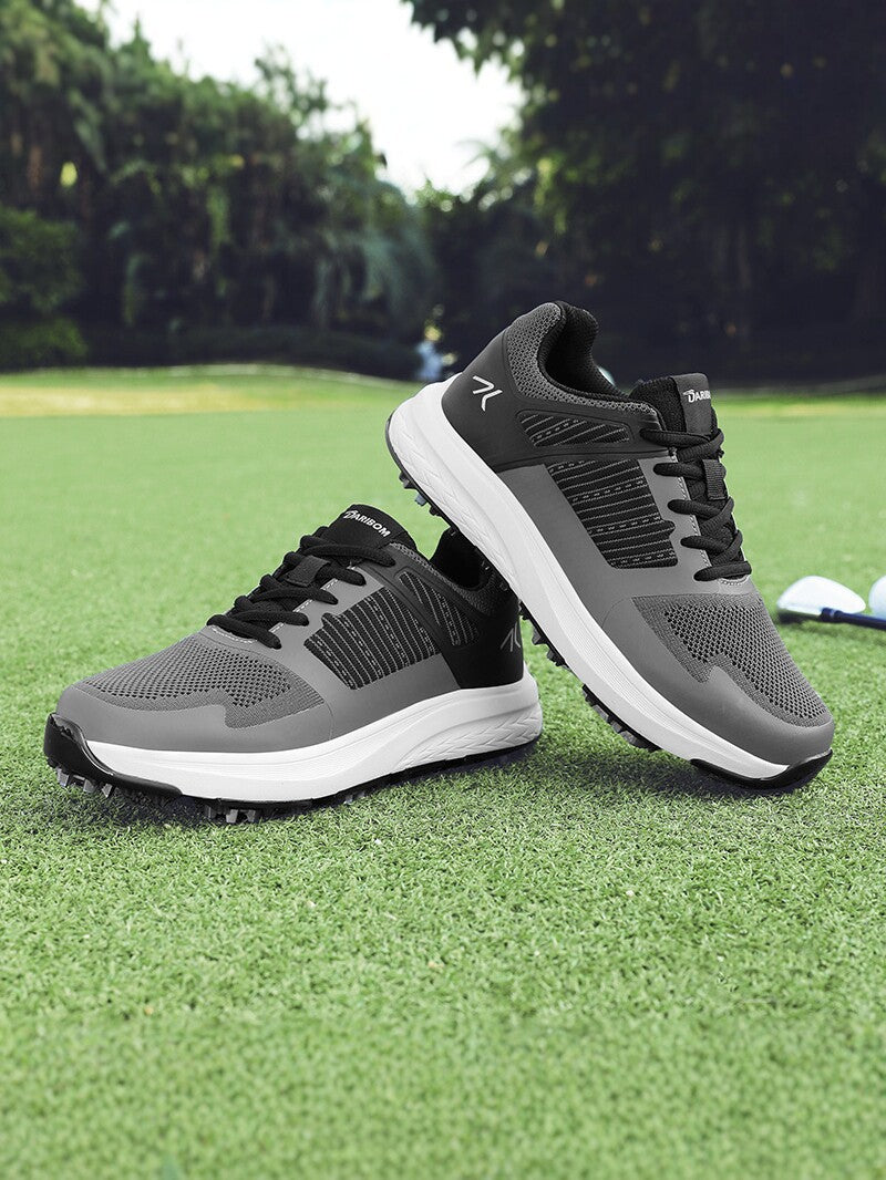 Pair of mens golf shoes photographed on green grass beside a golf club