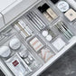 Several clear ribbed trays dividing a drawer of makeup, brushes and skincare