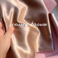 Cameo brown glossy silk pillowcase held in a hand over a pink gift box