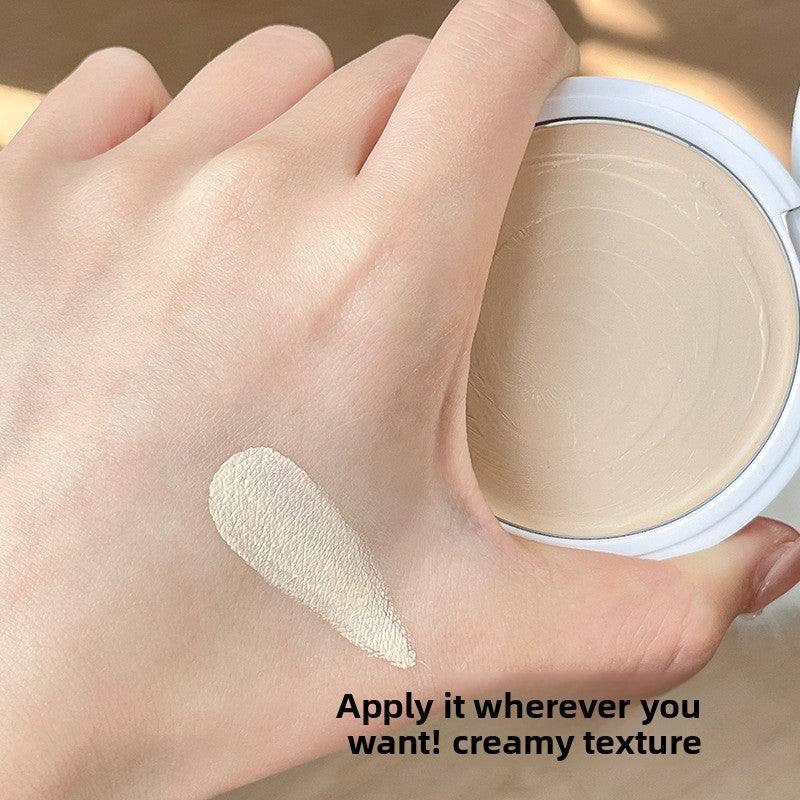 Creamy highlighter swatch on the back of the hand next to the compact