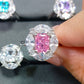 Close up of a pink radiant cut simulated diamond stone ring framed by clear marquise accent stones on a fingertip