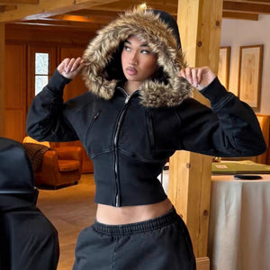 Model in a black cropped fur trimmed hooded zip jacket with a tan plush fur hood raised around the face