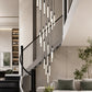 Spiral LED chandelier of slim tube lights hanging above a staircase with a glass balustrade