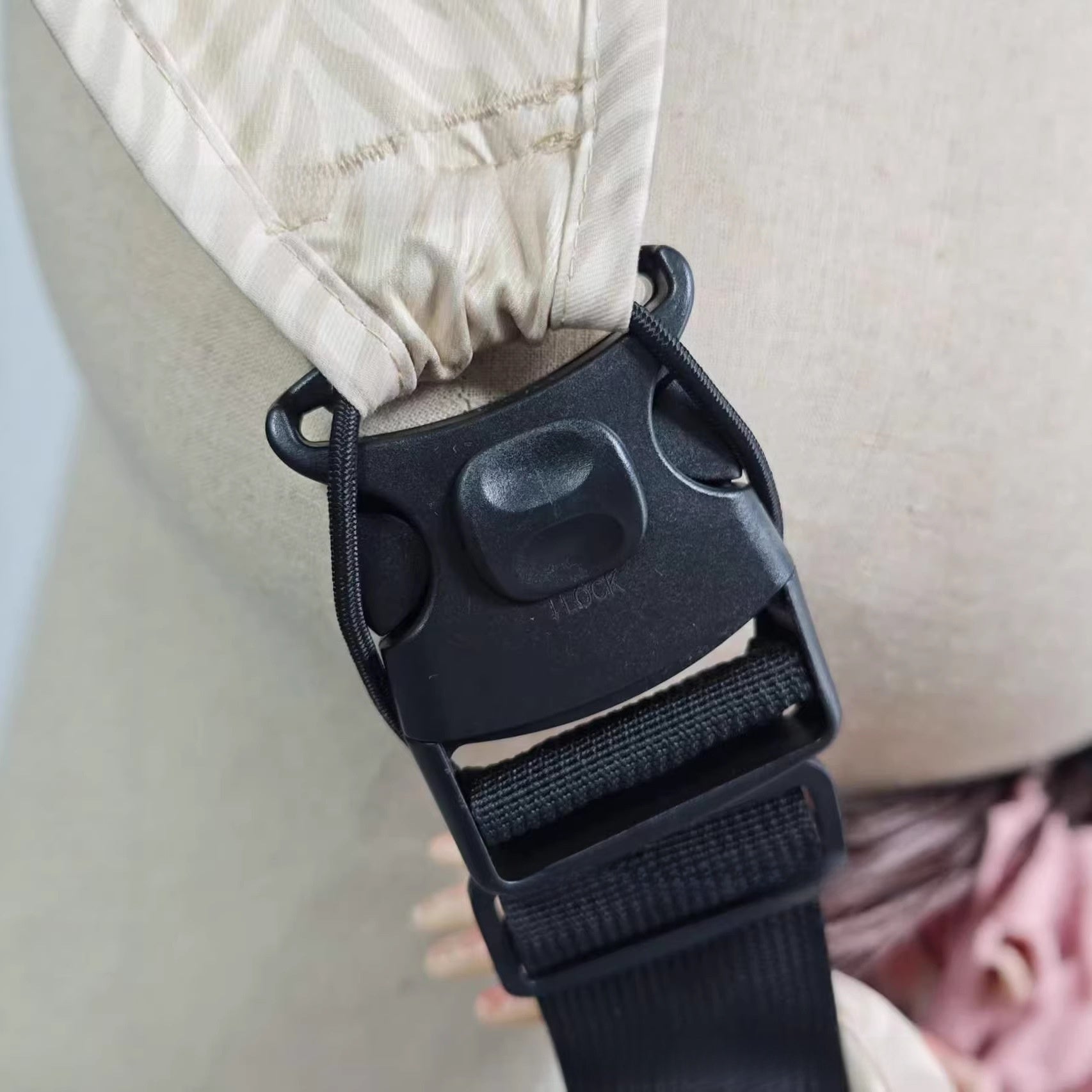 Close view of the padded shoulder band and webbing strap on the baby sling