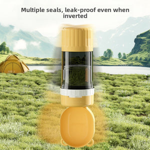 Yellow portable pet water bottle with clear body and fold out bowl standing on grass by a tent