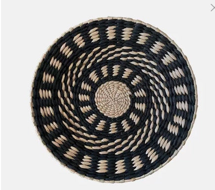 Natural straw woven wall ornament resting against a light neutral background