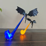 Black 3D printed dragon ornament over a lit orange and blue sculpted flame base on a wood desk