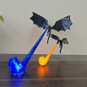 Black 3D printed dragon ornament over a lit orange and blue sculpted flame base on a wood desk