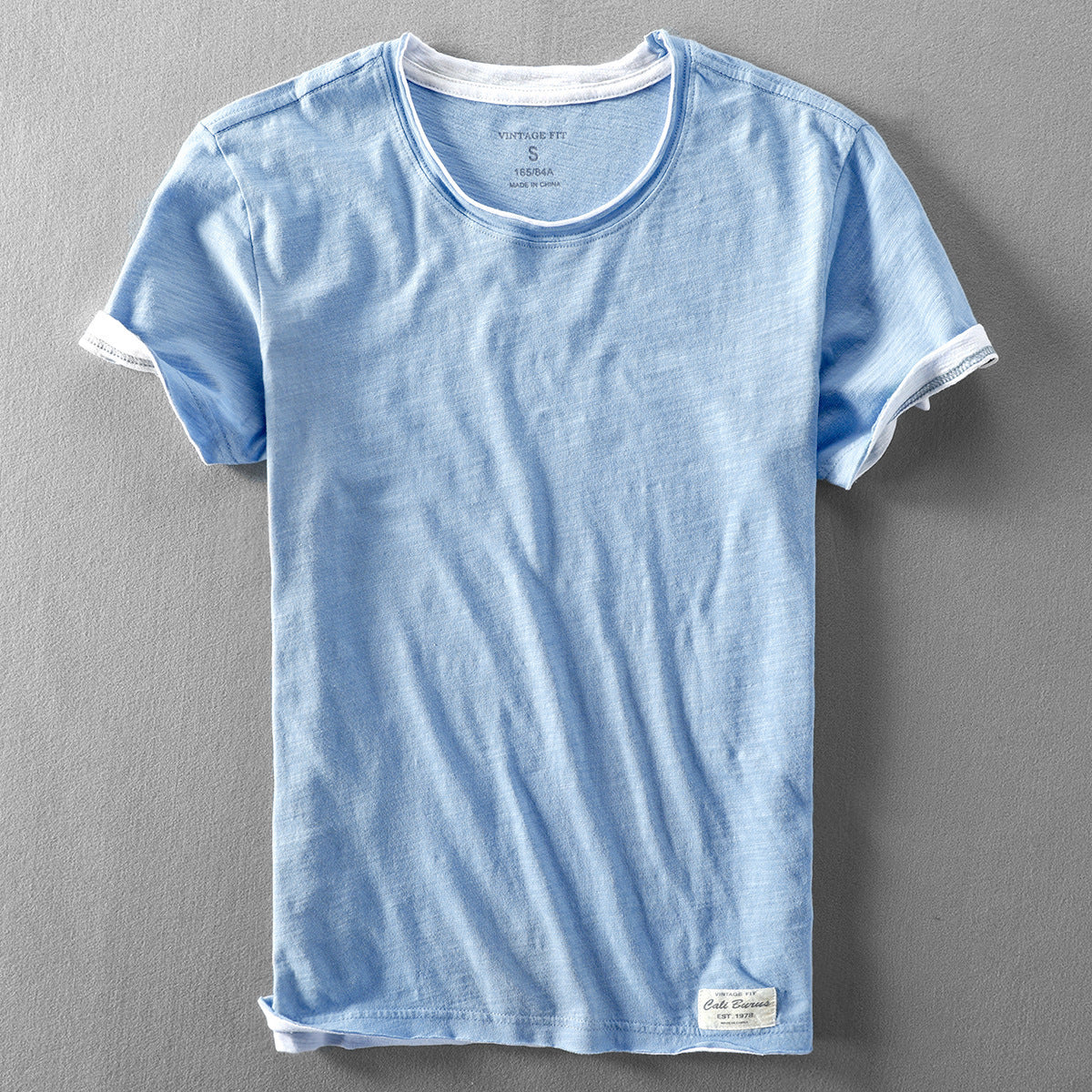 Light blue washed slub cotton short sleeve tee with dropped raw hem, front flat lay, size XL