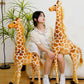 Woman on a white sofa between two tall giraffe plush toys with a smaller one and a leafy plant