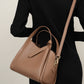 Khaki bucket bag worn crossbody with adjustable strap and gold clasp